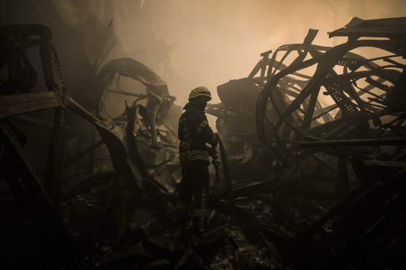 A Ukrainian firefighter inspects a food storage facility that was destroyed by an airstrike on the outskirts of Kyiv.