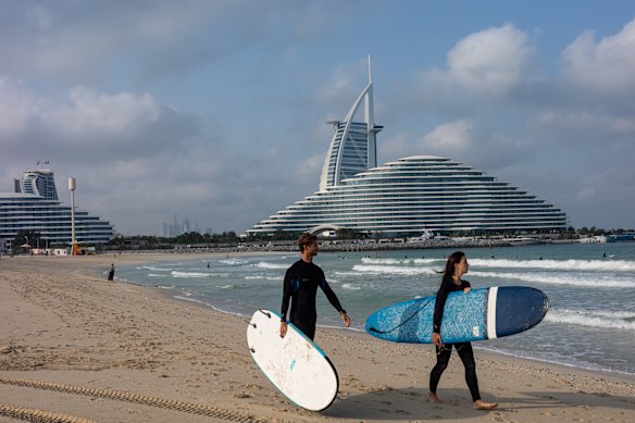 People prepare to surf on Jumeirah Beach, backed by the Burj al Arab hotel on March 5 in Dubai.