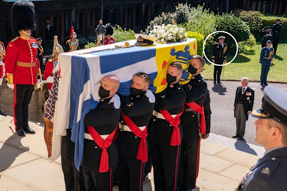 Commodore Guy Holthouse, standing to the right of the coffin and wearing a white hat, watches as the procession enters St George’s Chapel.