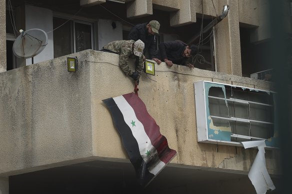 Rebel fighters remove a Syrian flag from a government building in Salamiyah, near Homs, on Saturday. 