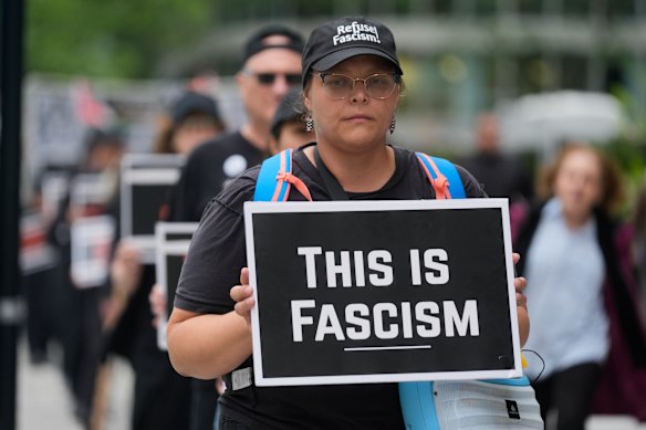 Ella Fowler carries a sign as she and other anti-Trump, anti-fascism protesters march as part of the “Good Trouble Lives On” national day of action, in Chicago.
