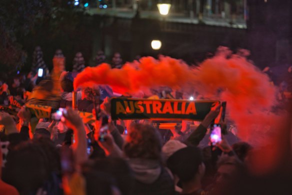 Flare light illuminates the crowd of soccer fans at Federation Square on Thursday morning.
