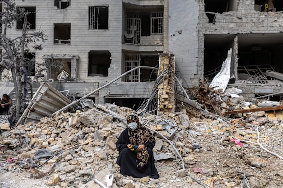 A woman sits on the rubble of residential buildings destroyed by US and Israeli strikes in eastern Tehran. 