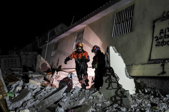 Mexican firefighters search rubble in the town of Les Cayes.