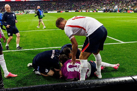 England’s Dan Burn helps Jordan Henderson after he fell over an advertising hoarding.