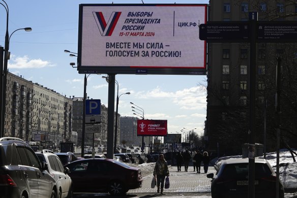 People walk past a billboard promoting the upcoming presidential election with words “Together – we are force!” in Moscow on Tuesday.