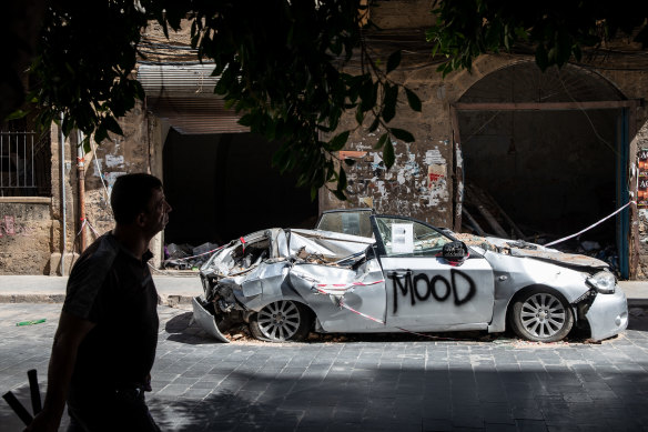 A man walks past a car that was destroyed in the blast it Beirut's port on August 4.