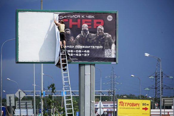 A man takes down the poster with writing reading “Join us at Wagner”, which is associated with the owner of the Wagner private military contractor, Yevgeny Prigozhin, is seen above a highway on the outskirts of St Petersburg.