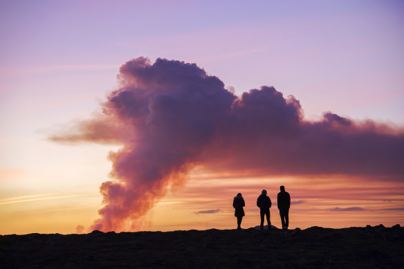 People watch from the north as the volcano erupts near Grindavík.