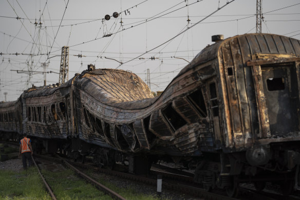 A railway worker stands next to heavily damaged train after a Russian attack on a train station.