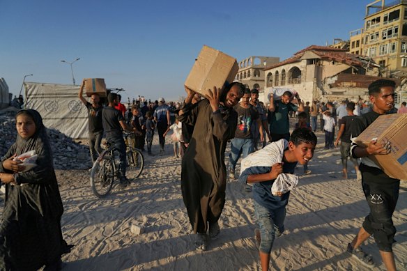 Palestinians carry sacks and boxes of food and humanitarian aid unloaded from a World Food Program convoy that had been heading to Gaza City, in the northern Gaza Strip