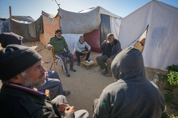 Tony Al-Masri, center left, sits with neighbours outside the tent he and his wife Amal Amouri, both Christians, share at the Muwassi tent camp near Khan Younis, Gaza Strip.