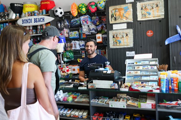 Owner of Souvenir plus, Ash Mehana, pictured serving customers at his Bondi shop on Tuesday.