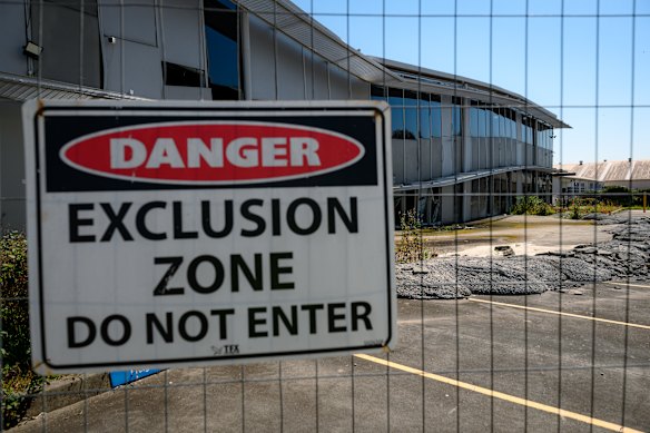 A danger sign on a fence near where  the sinkhole opened up beneath a two-storey warehouse in March 2024. 