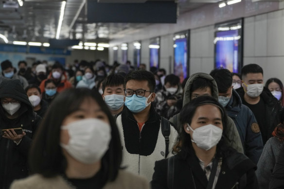 Masked commuters commute to work during the morning rush hour in Beijing in December 2022.