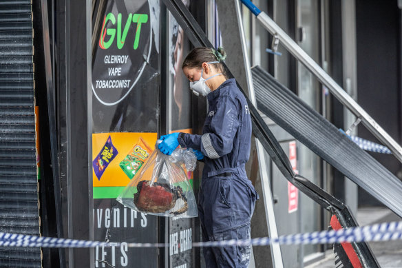 An investigator bags items from the scene of the tobacco shop fire in Glenroy.