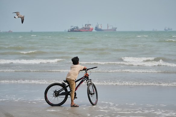 A boy on a beach overlooking commercial vessels anchored in the Strait of Hormuz off Bandar Abbas, Iran, this week.