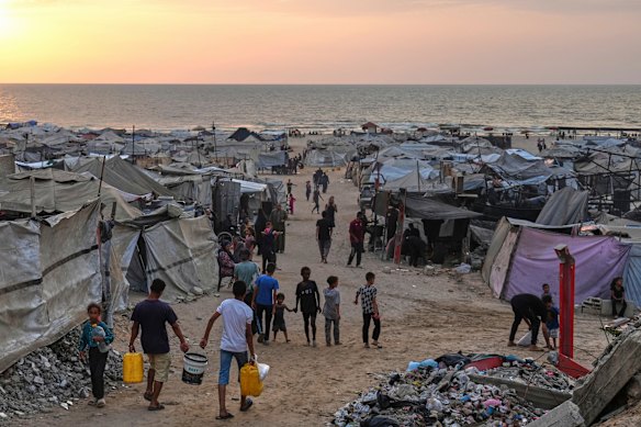 Os palestinos deslocados atravessam um acampamento improvisado ao longo da praia em Gaza City no domingo. 