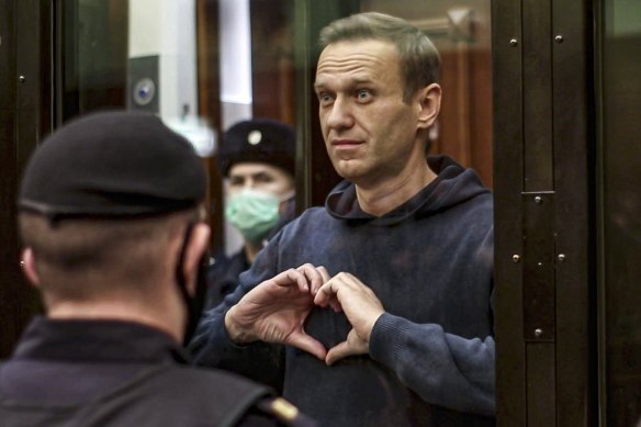 Russian opposition leader Alexei Navalny shows a heart symbol while standing in a cage for defendants in Moscow in 2021.