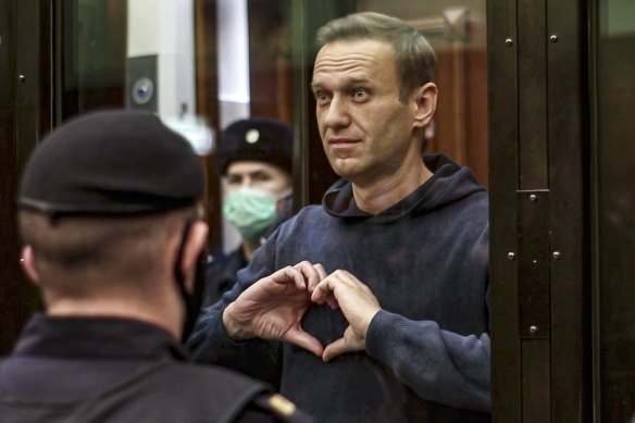 Russian opposition leader Alexei Navalny shows a heart symbol while standing in a cage for defendants in Moscow in 2021. 