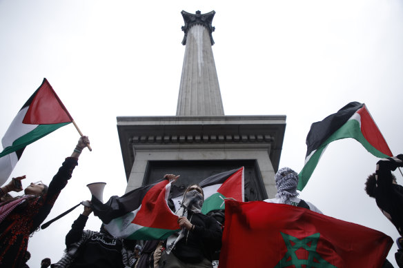 Demonstrators hold up flags and placards as they stand on the base of Nelson’s Column in Trafalgar Square during a pro-Palestinian demonstration in London.