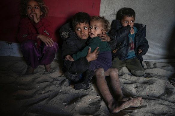 Palestinian Tamim Marouf, 6, sits inside his family’s tent alongside his sister Hala, 10, and his brother Malek, 4, at a camp for internally displaced Palestinians on the beachfront in Deir al-Balah, central Gaza Strip.