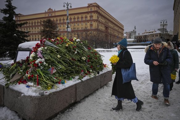 People lay flowers paying the last respect to Alexei Navalny at the monument with the historical Federal Security Service (FSB, Soviet KGB successor) building in the background.