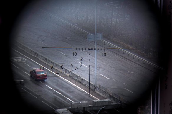 A car driving along a road is visible from a Ukrainian army position through the viewfinder of a Dragunov sniper rifle in the northern part of Kyiv, Ukraine, on March 1.