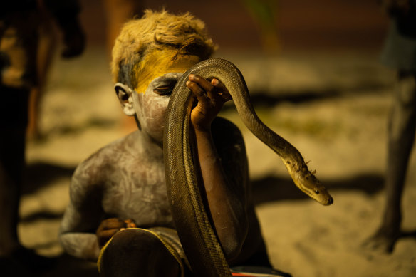 A young boy shows off his pet python.