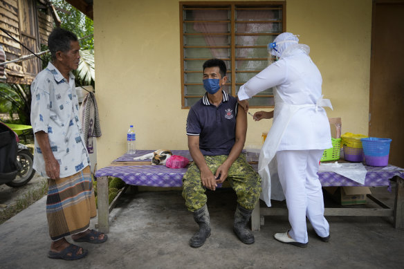A nurse administers a Pfizer vaccine to a farmer outside his home in Sabab Bernam, a rural area in the state of Selangor.