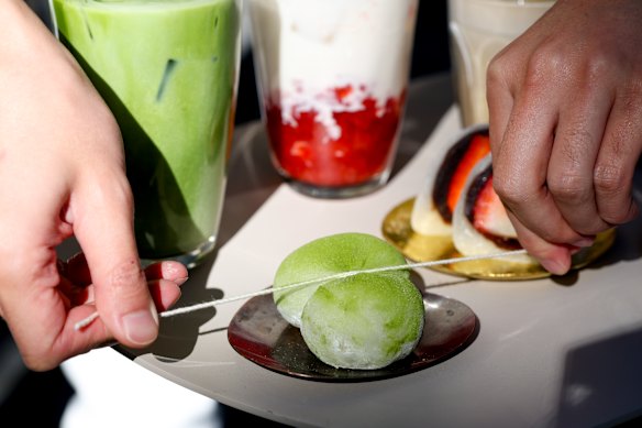 Splitting a matcha flavoured daifuku with a piece of string at Sydney Daifuku Store.