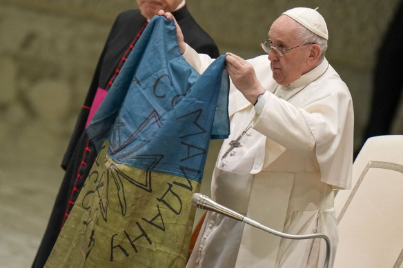 Pope Francis shows a flag that was brought to him from Bucha, Ukraine, earlier this month.
