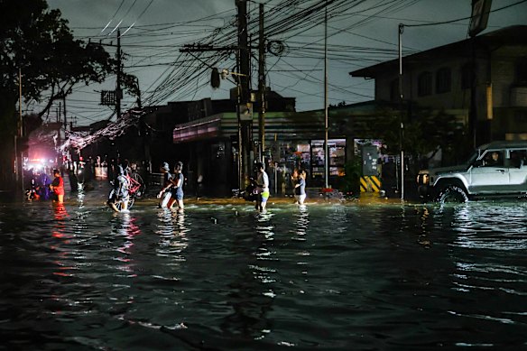 People wade through flooded streets amid a blackout as super Typhoon Fung-Wong hit the Philippines on Monday.
