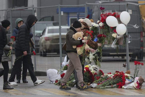 People place flowers and toys at the fence next to the Crocus City Hall, on the western edge of Moscow.