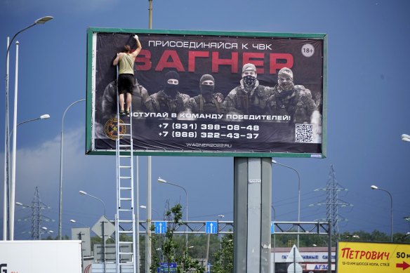 A man prepares to take down a poster reading “Join us at Wagner”  along a highway on the outskirts of St Petersburg on Saturday.