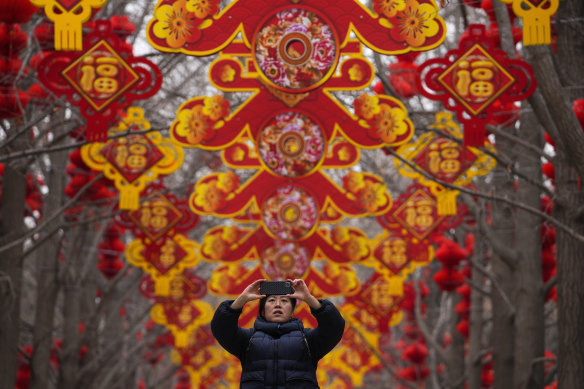 A woman photographs lanterns and decorations to mark Chinese Lunar New Year in a Beijing park.