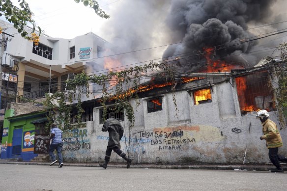 Firefighters run to a restaurant that was set on fire during a protest in Port-au-Prince.