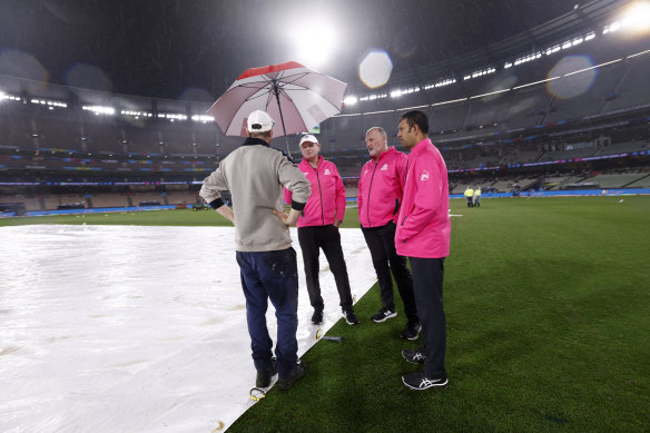 MCG curator Matt Page confers with umpires at the MCG on Friday night.