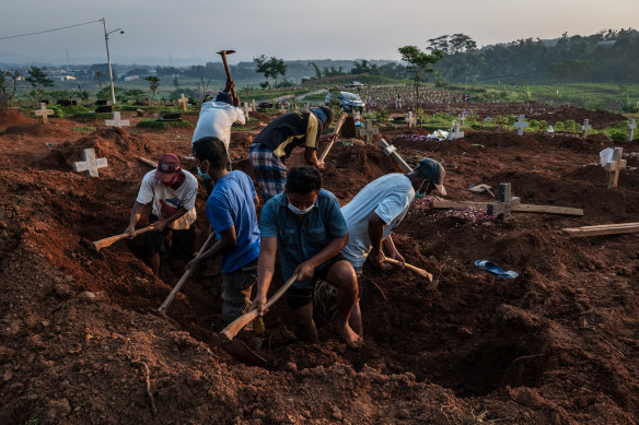 Grave diggers conduct a burial at Jatisari public cemetery, reserved for suspected COVID-19 victims, in Semarang, Central Java.