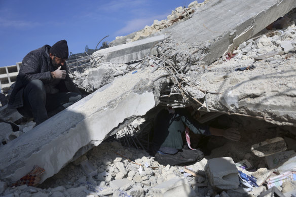 People try to remove their furniture and household appliances out of a collapsed building  in the town of Jinderis, Aleppo province, Syria, following the earthquake.