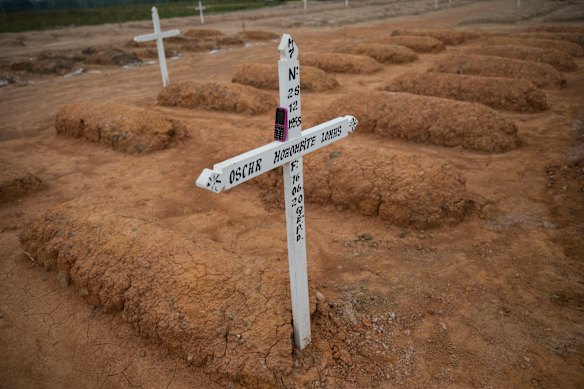 A gravedigger's phone rests on a cross marking the grave of a COVID-19 victim at a new cemetery for victims of the pandemic on the outskirts of Pucallpa, Peru.