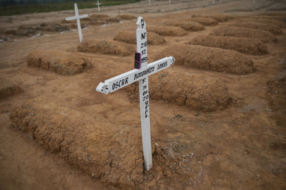 A gravedigger's phone rests on a cross marking the grave of a COVID-19 victim at a new cemetery for victims of the pandemic on the outskirts of Pucallpa, Peru.