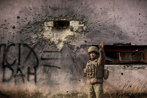 A Ukrainian serviceman points to the direction of the incoming shelling next to a building which was hit by a large caliber mortar shell in the frontline village of Krymske, Luhansk region, in eastern Ukraine, on Saturday February 19.