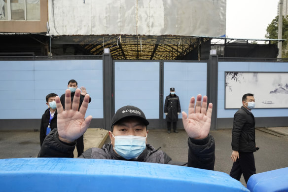 A security guard waves for journalists to clear the road after a convoy carrying the World Health Organisation team entered the Huanan Seafood Market in January 2021.