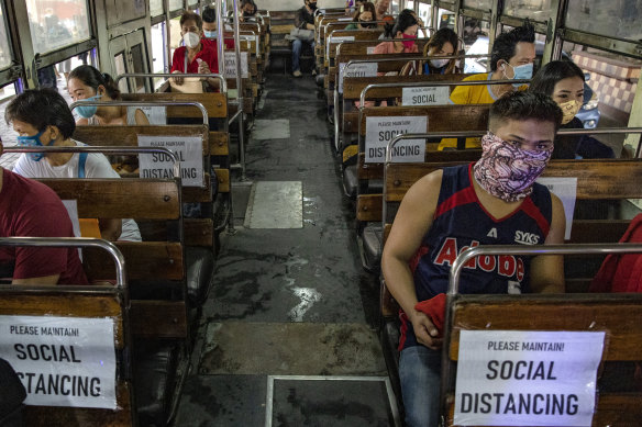 Commuters sit on a bus with seats spaced to observe social distancing in Manila on Monday.
