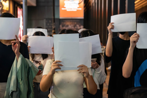 People hold sheets of blank paper in protest of COVID restriction in mainland as police setup cordon during a vigil in the central district  in Hong Kong, China.