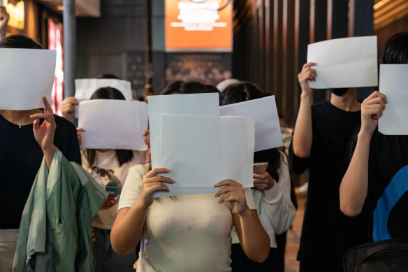 People hold sheets of blank paper in protest of COVID restriction in mainland as police setup cordon during a vigil in the central district  in Hong Kong, China. 