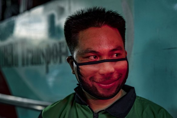 A worker wearing a novelty face mask is illuminated by a traffic light in Manila on Monday, the first day of relaxed quarantine measures.