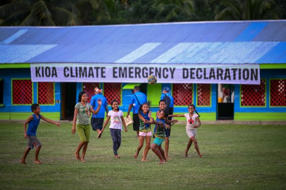 Children play soccer on the grass in Kioa. 