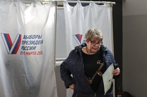 A woman leaves a voting booth at a polling station at a school in port city of Vladivostok. 